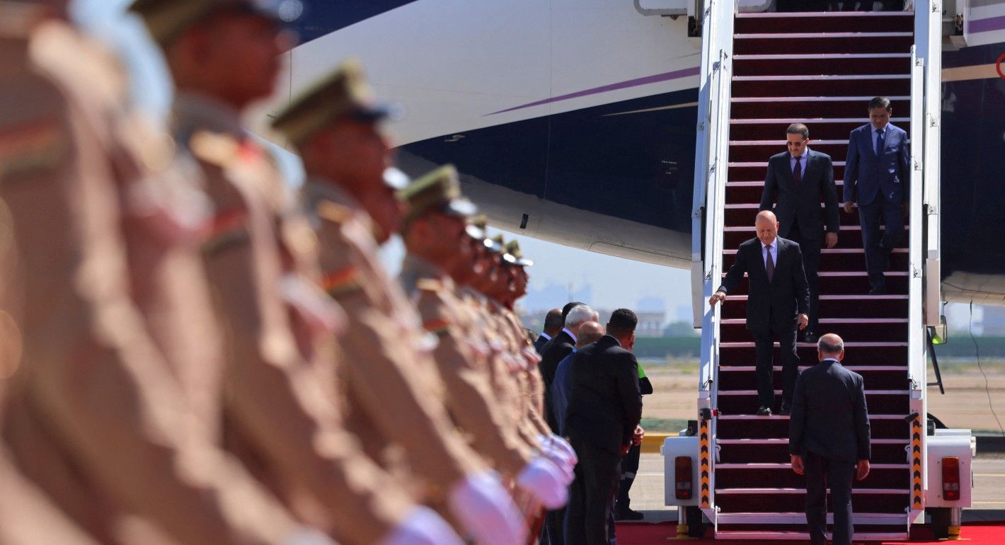 Three men descend a plane onto a red carpet. Men in uniform line the carpet as an honor processional.