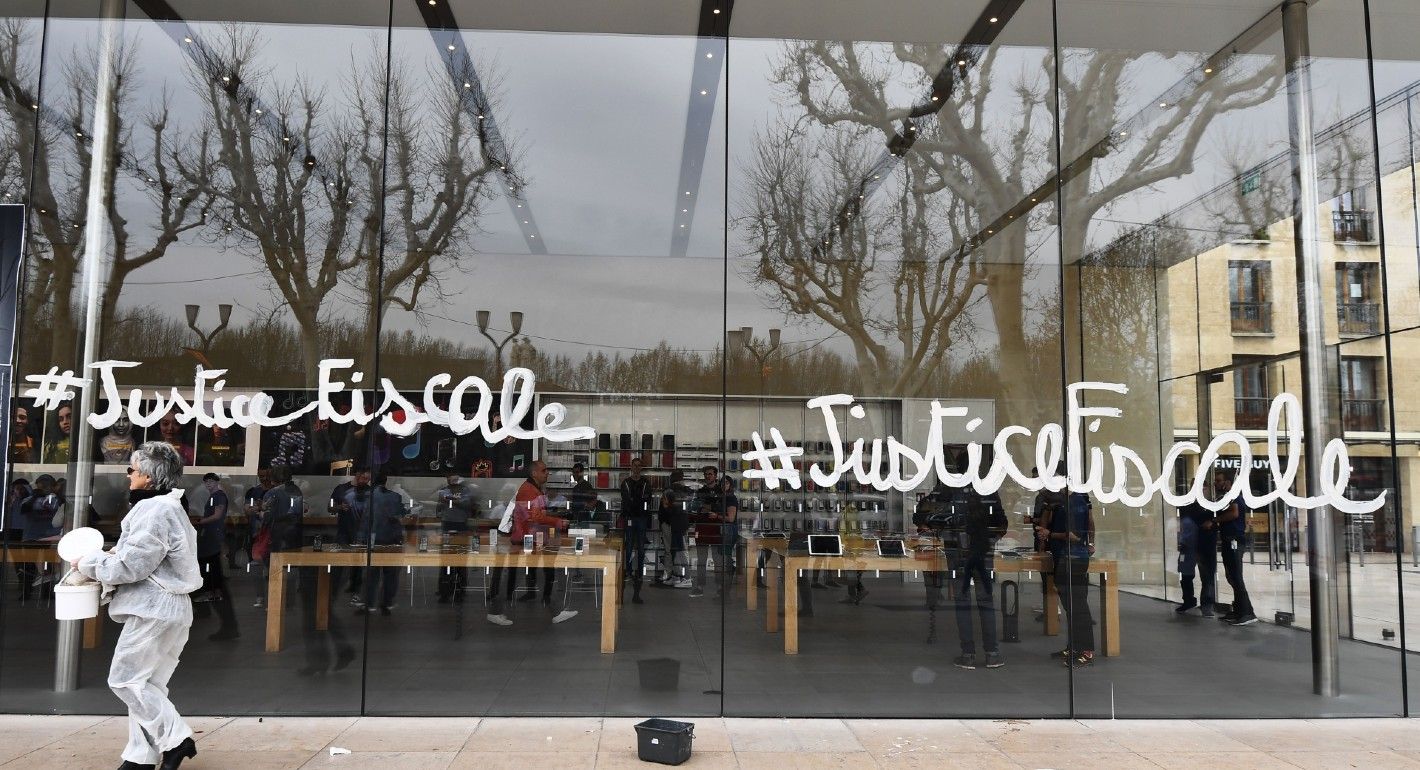 An activist of the Association for the Taxation of financial Transactions and Citizen's Action (ATTAC) walks after painting on the Apple Store window 