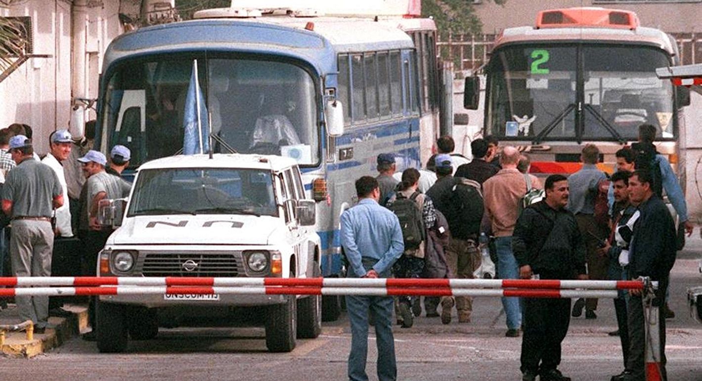 People in the street mill around two large busses and a white UN Jeep