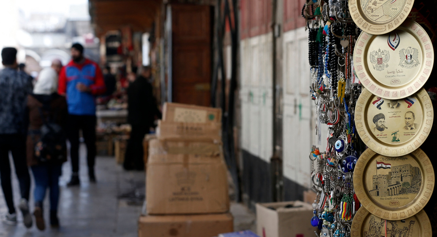 Right side of image features Syrian souvenirs like plates and keychains. Blurry people are shopping in the background