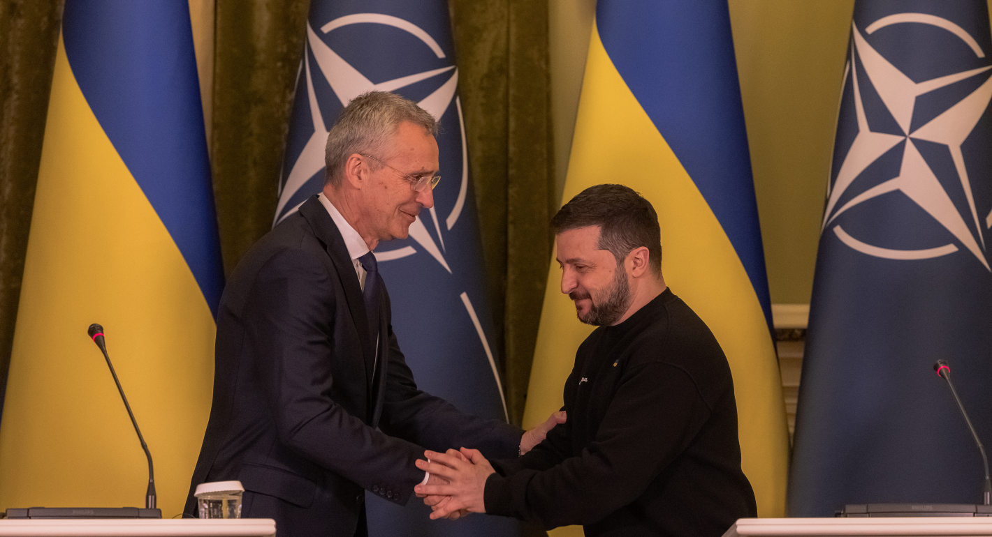 Zelensky and Stoltenberg shake hands in front of Ukrainian and NATO flags, respectively