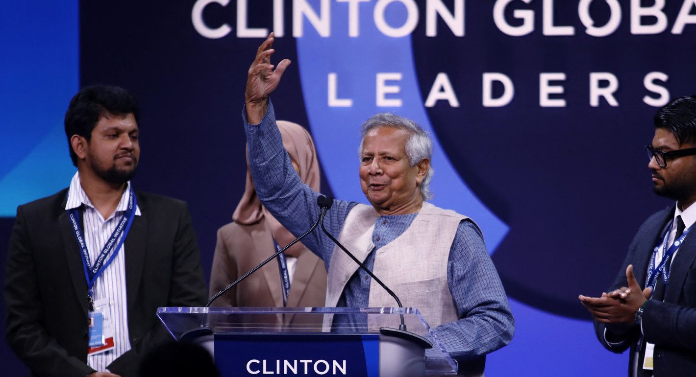 Muhammad Yunus speaking into a mic with his hand raised