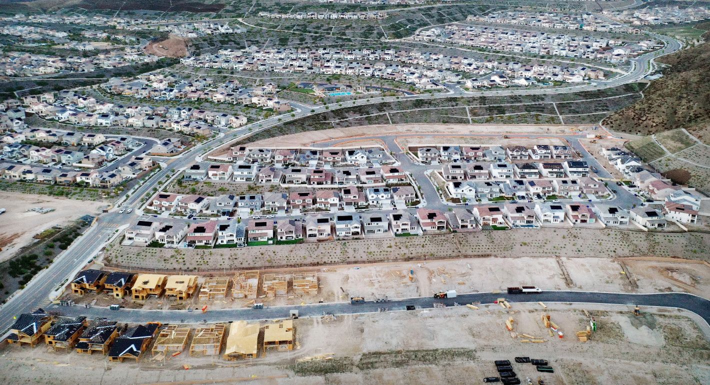  An aerial view of homes in a housing development with new houses under construction at bottom