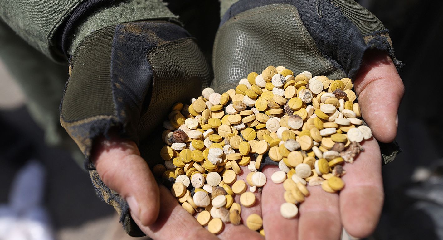Fighters affiliated with Syria's "Hayat Tahrir al-Sham" (HTS) rebel-group display drugs previously seized at a checkpoint they control in Daret Ezza, in the western countryside of the northern Aleppo province, on April 10, 2022