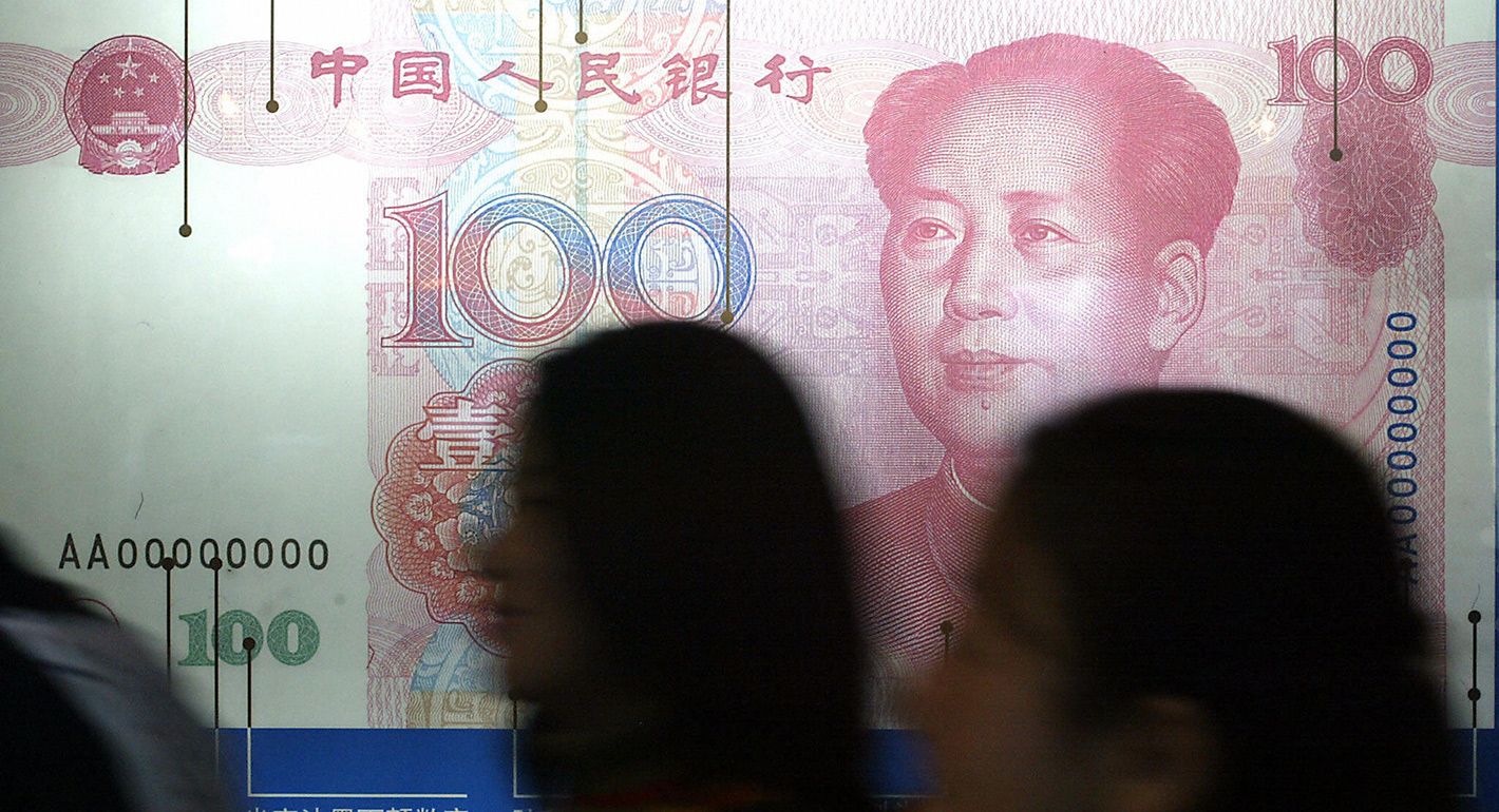 Visitors walk past a poster of a Chinese 100-yuan note at an exhibition in Beijing 