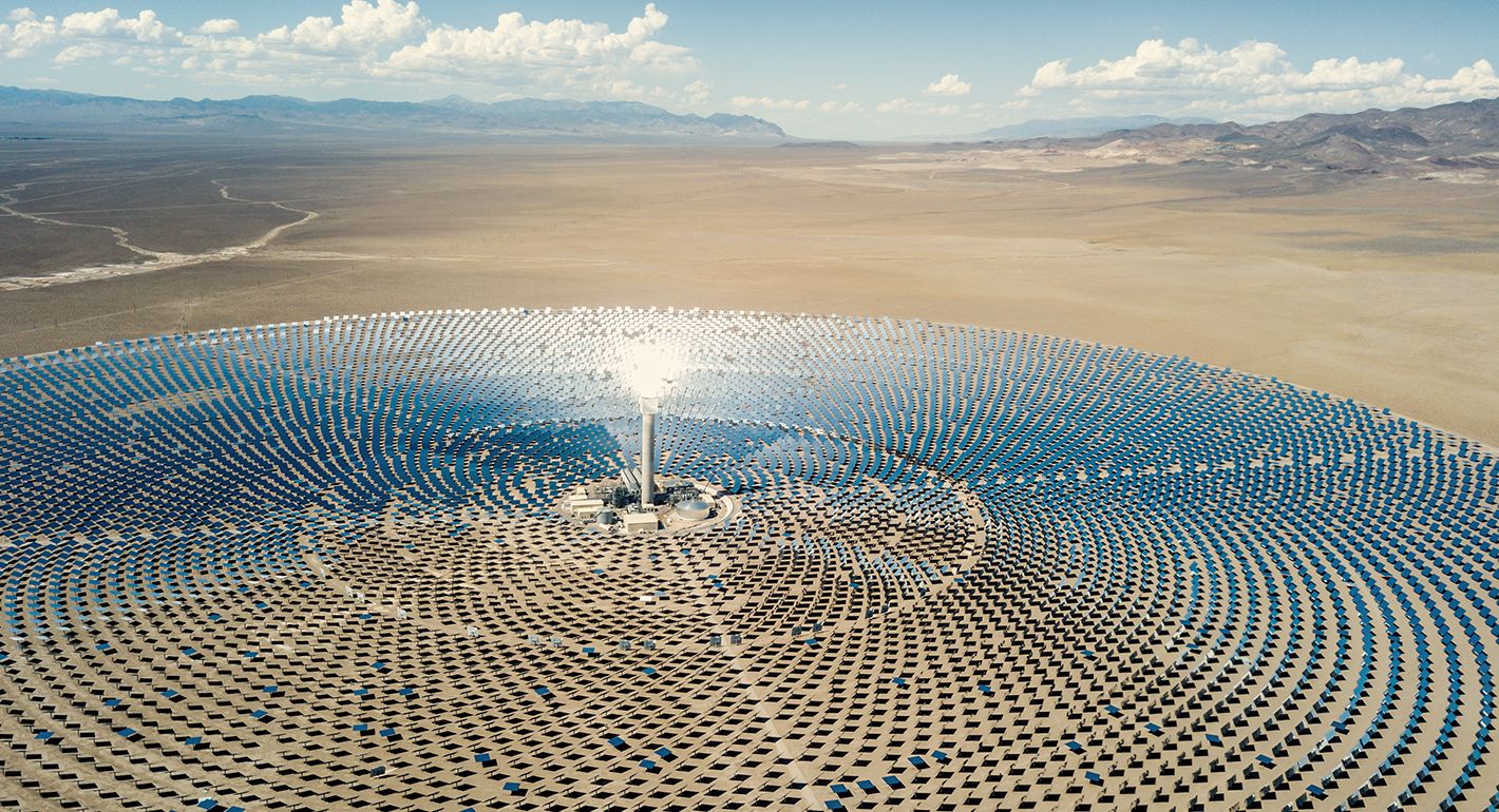 Aerial view from a drone down to large solar thermal power station in the dry desert landscape to the horizon