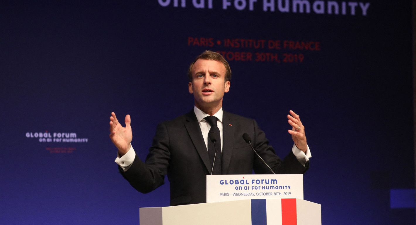 Macron gesturing as he speaks at a dais