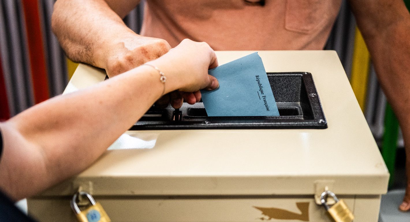 A person drops a ballot in a locked ballot box