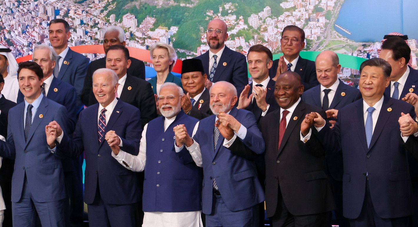 Men (and one woman) smiling for a posed photo while holding hands