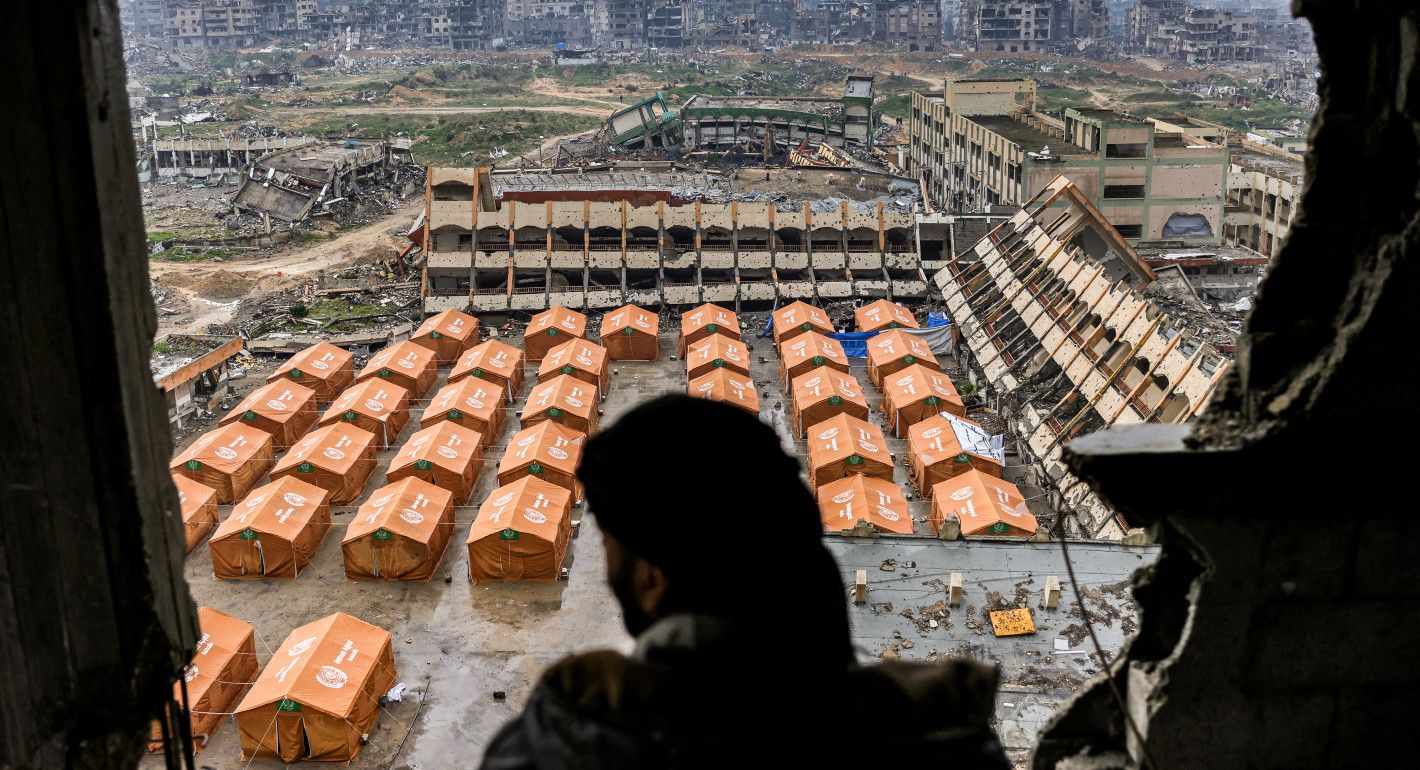 An outline of a man in the foreground, with a wide view of rows of orange tents in the background