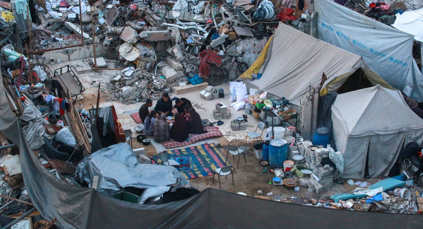 family eating amid tents and rubble