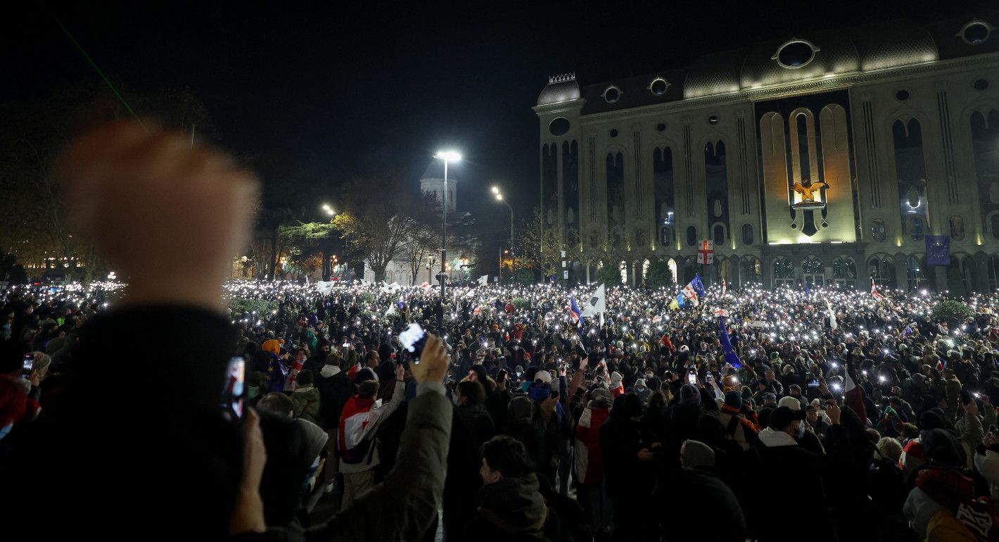 people holding up lights, protesting in front of a government building