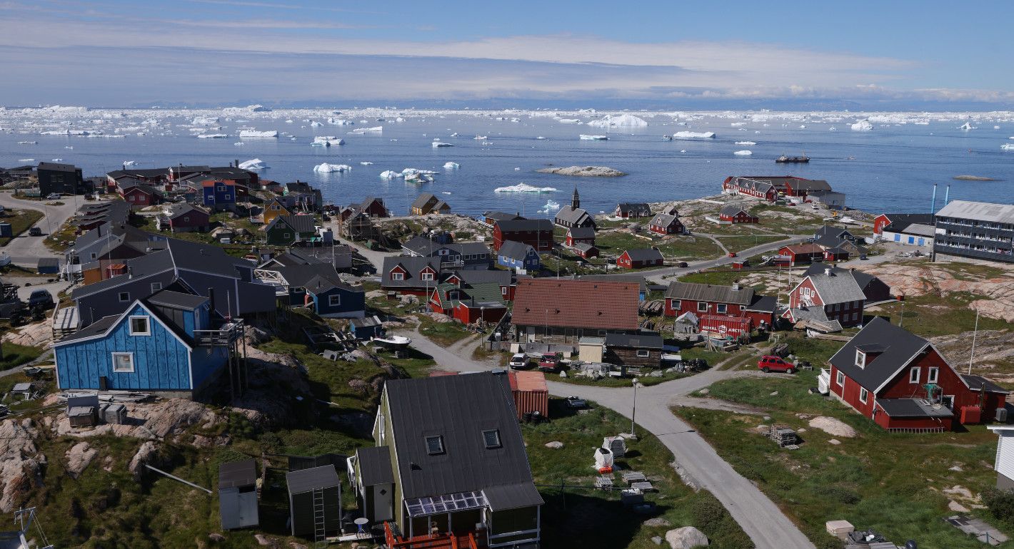 houses on the shore, while icebergs float in the water