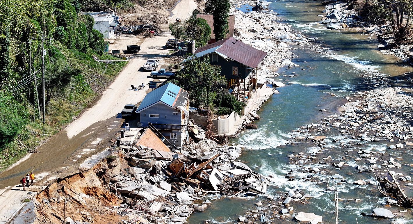 An aerial view of people standing near destroyed and damaged buildings in the aftermath of Hurricane Helene flooding on October 8, 2024 in Bat Cave, North Carolina. 