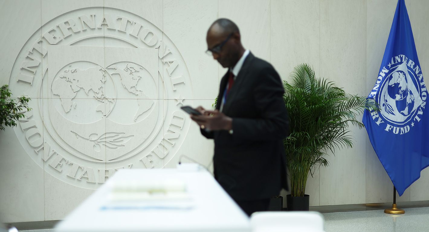 A man reads his phone during the annual Spring Meetings at the IMF headquarters on April 15, 2024 in Washington, DC.