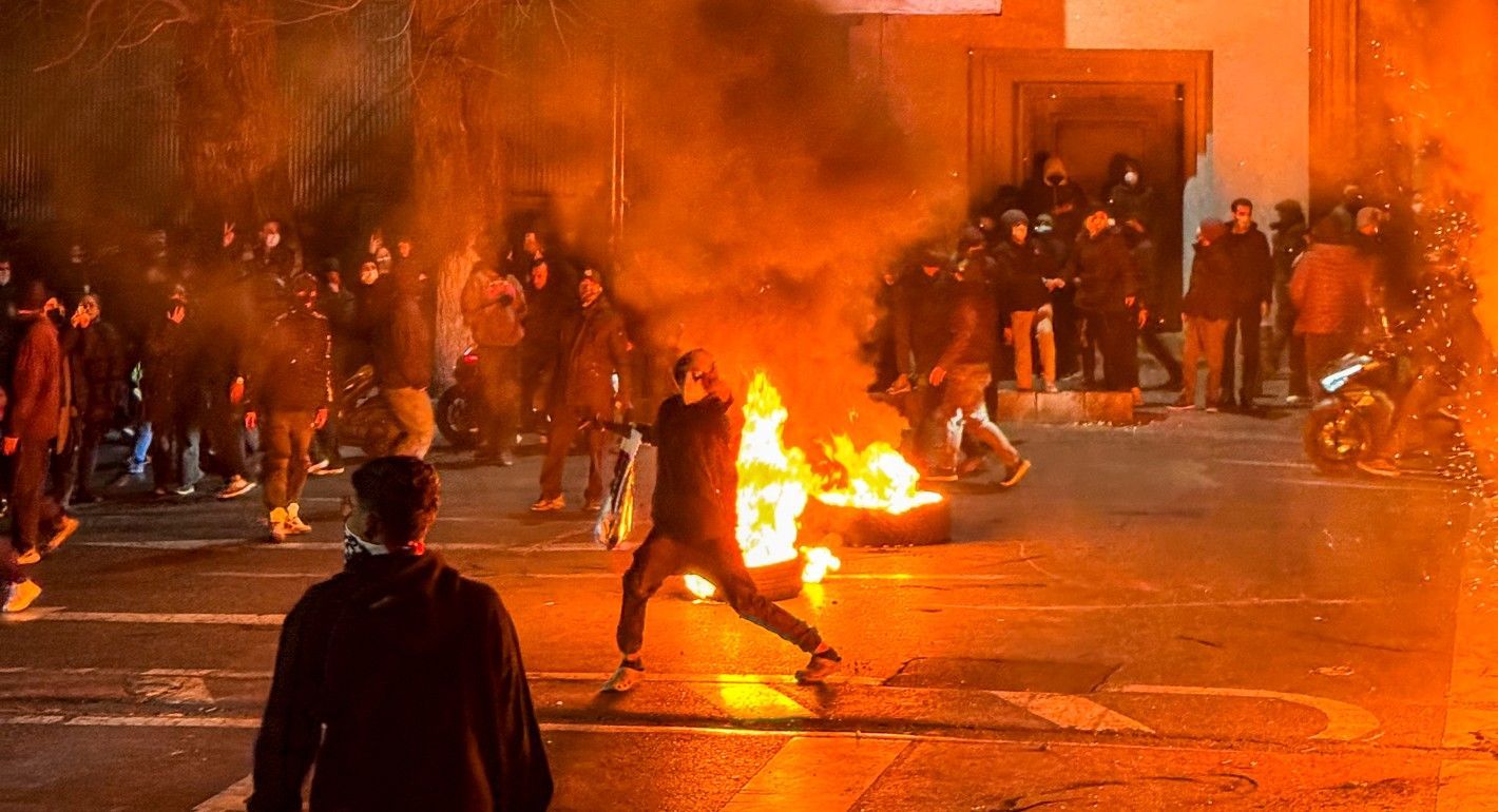 Tires on fire in the middle of the street while people protest