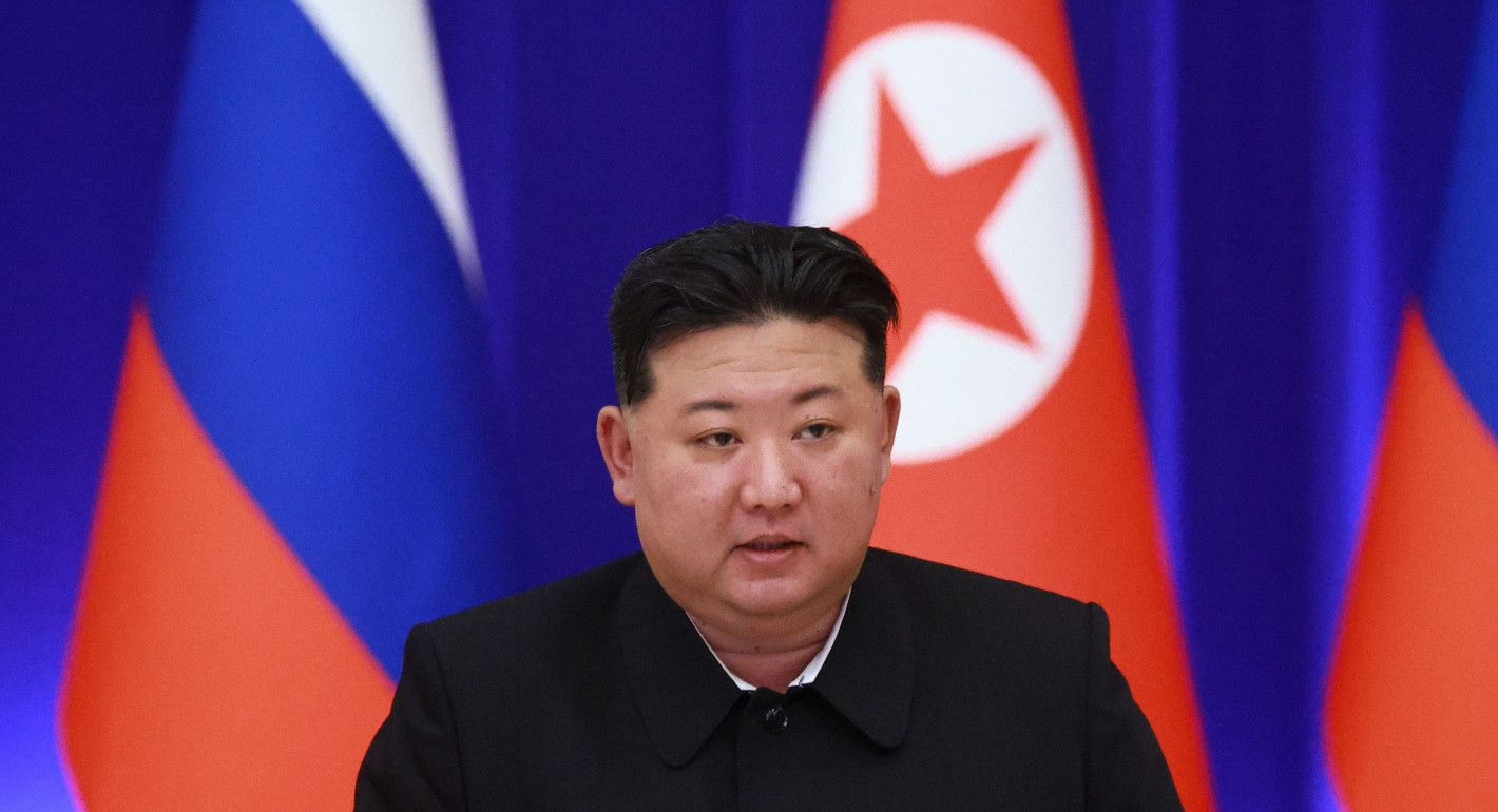 Kim Jong Un, with North Korean and Russian flags in the background