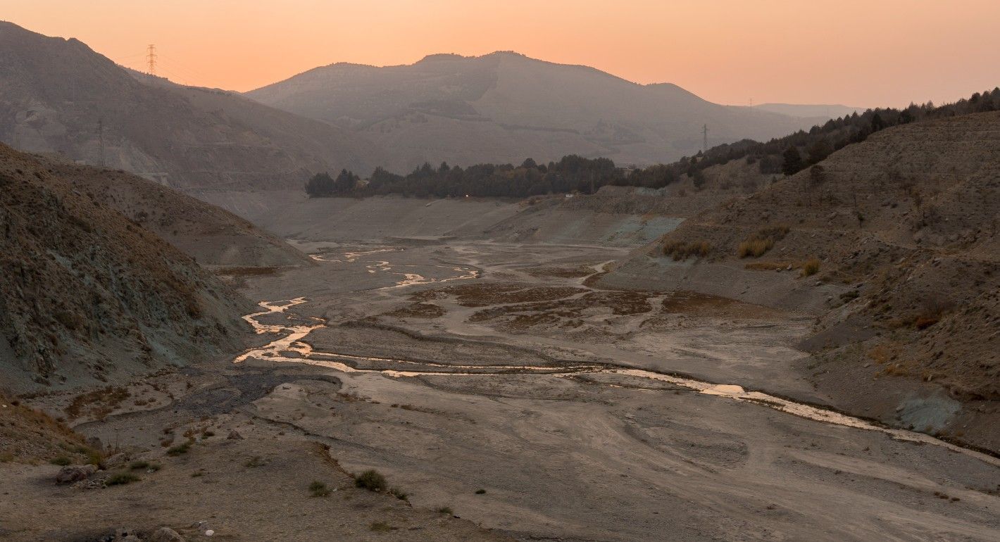dry riverbed with only a tiny ribbon of water running through it