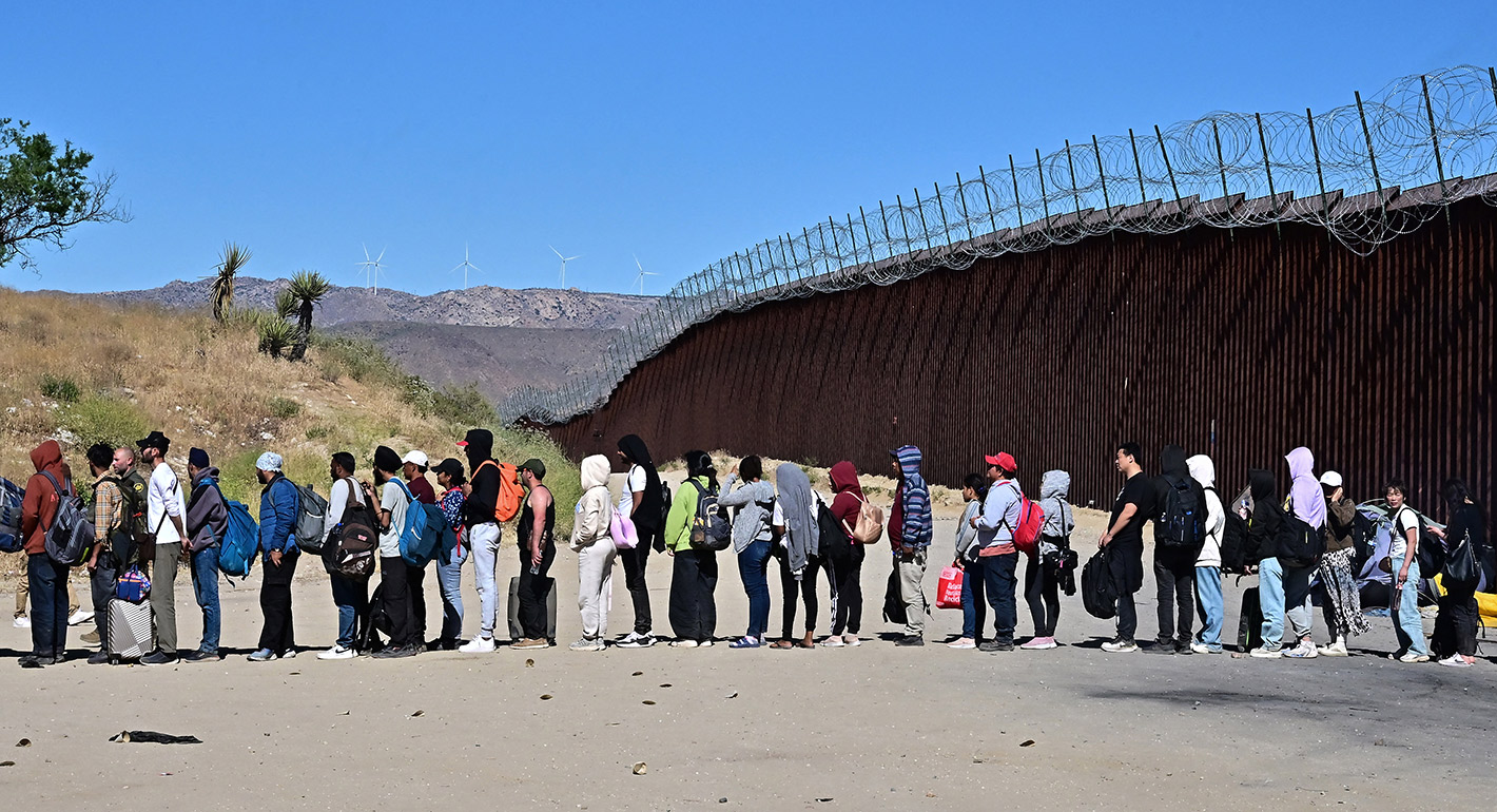  Migrants wait in line hoping for processing from Customs and Border Patrol agents after groups arrived at Jacumba Hot Springs, California, after walking under intense heat from Mexico into the US on June 5, 2024.