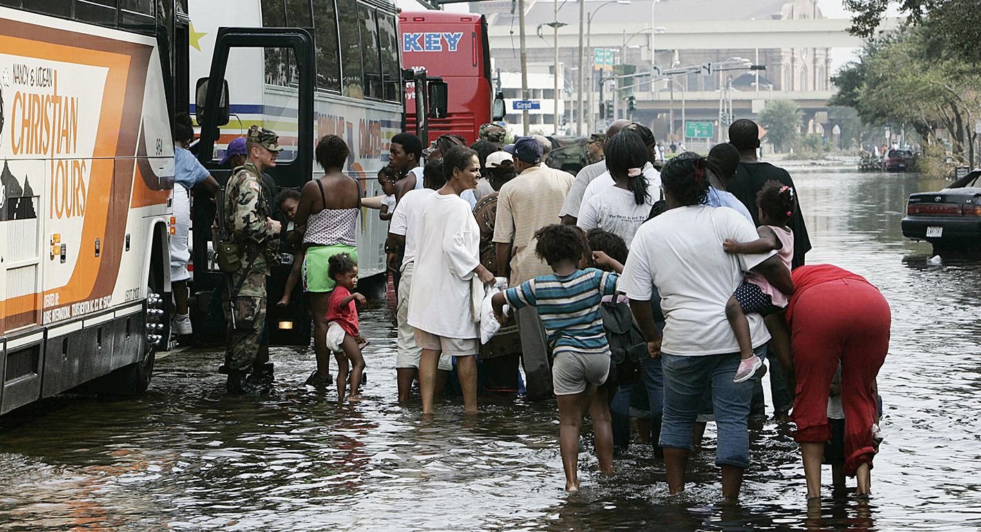 Soldiers watch people boarding buses, wading through water near the Superdome in New Orleans on 01 September, 2005