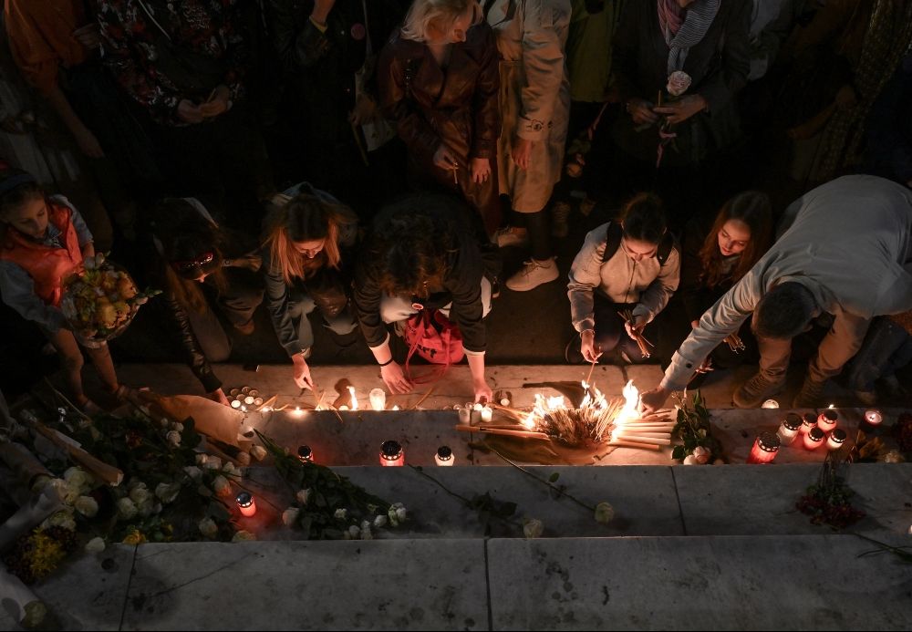 people putting flowers and candles on steps