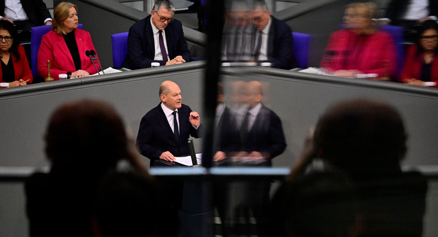 Olaf Scholz speaking on the left, with  image mirrored but blurry on the right 