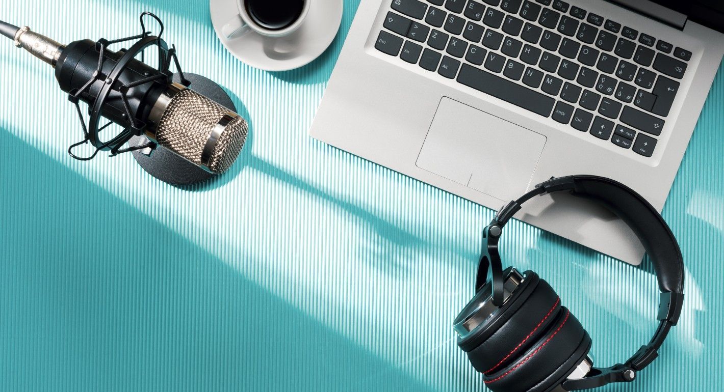 overhead view of laptop, headphones, coffee, and mic