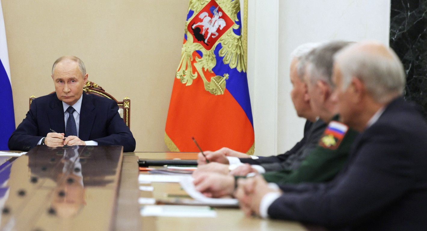 Putin sitting at long table with generals on the end