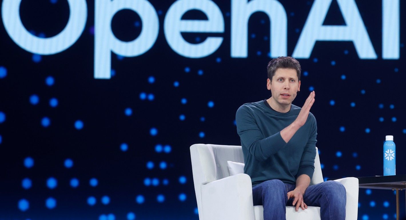 Altman sitting in a chair on a stage
