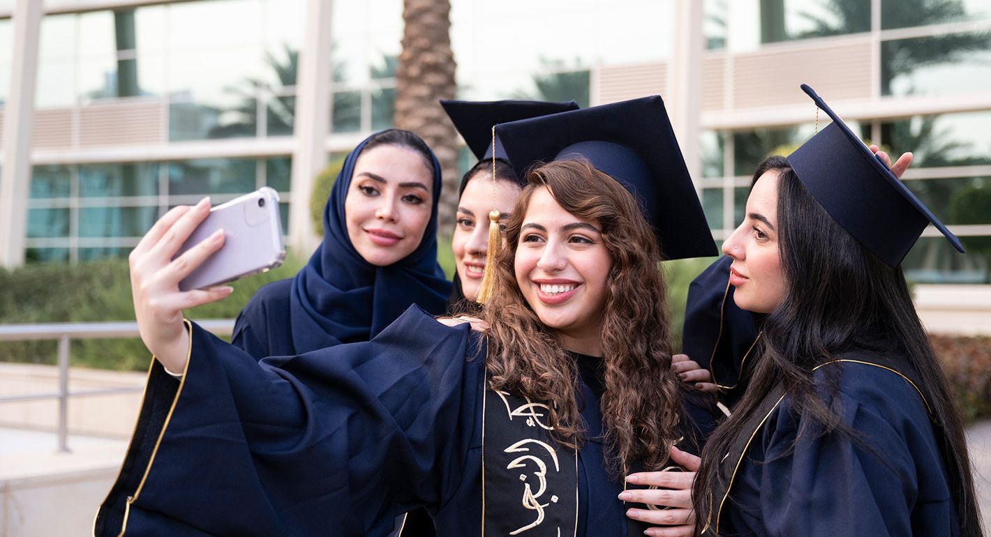 Female students taking selfie with their professor on graduation day