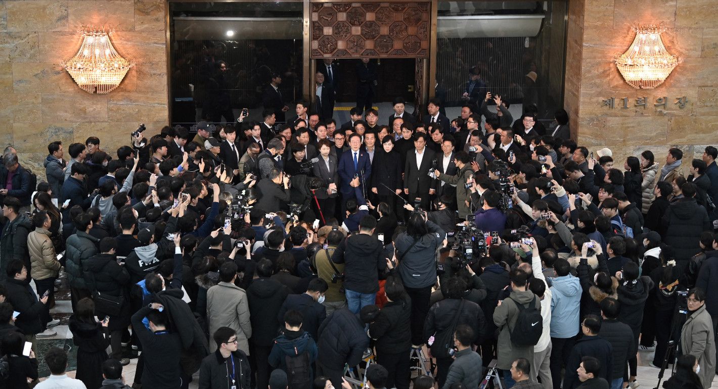 crowd gathered around one man speaking into a mic