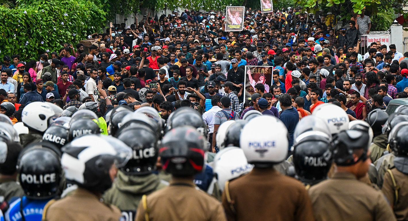 Policemen stand guard as protestors take part in an anti-government demonstration by the university students demanding the release of their leaders, in Colombo on October 18, 2022