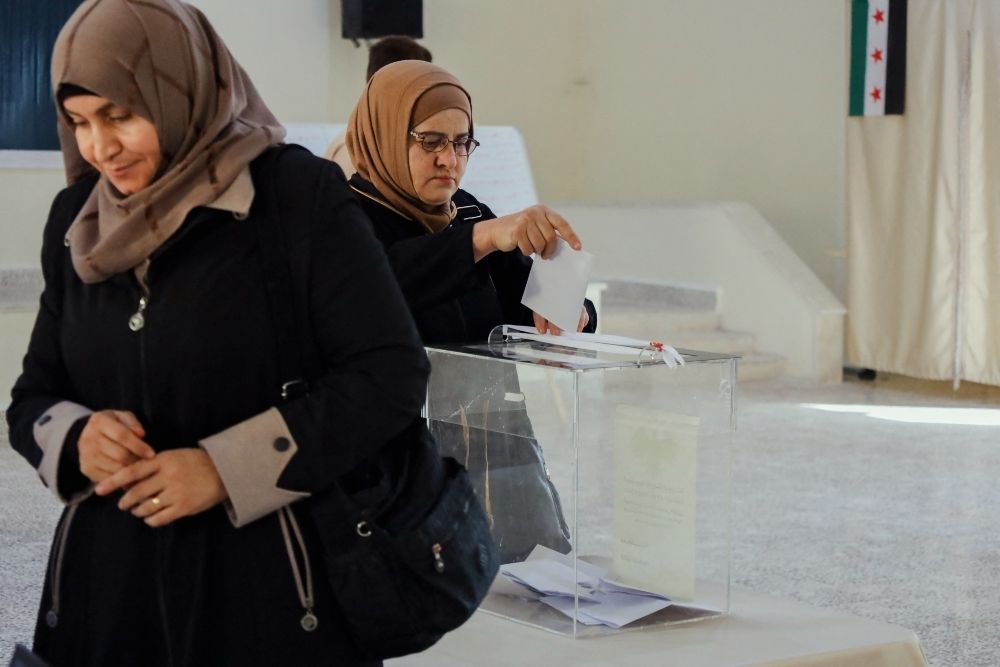 a woman putting a vote in a clear ballot box