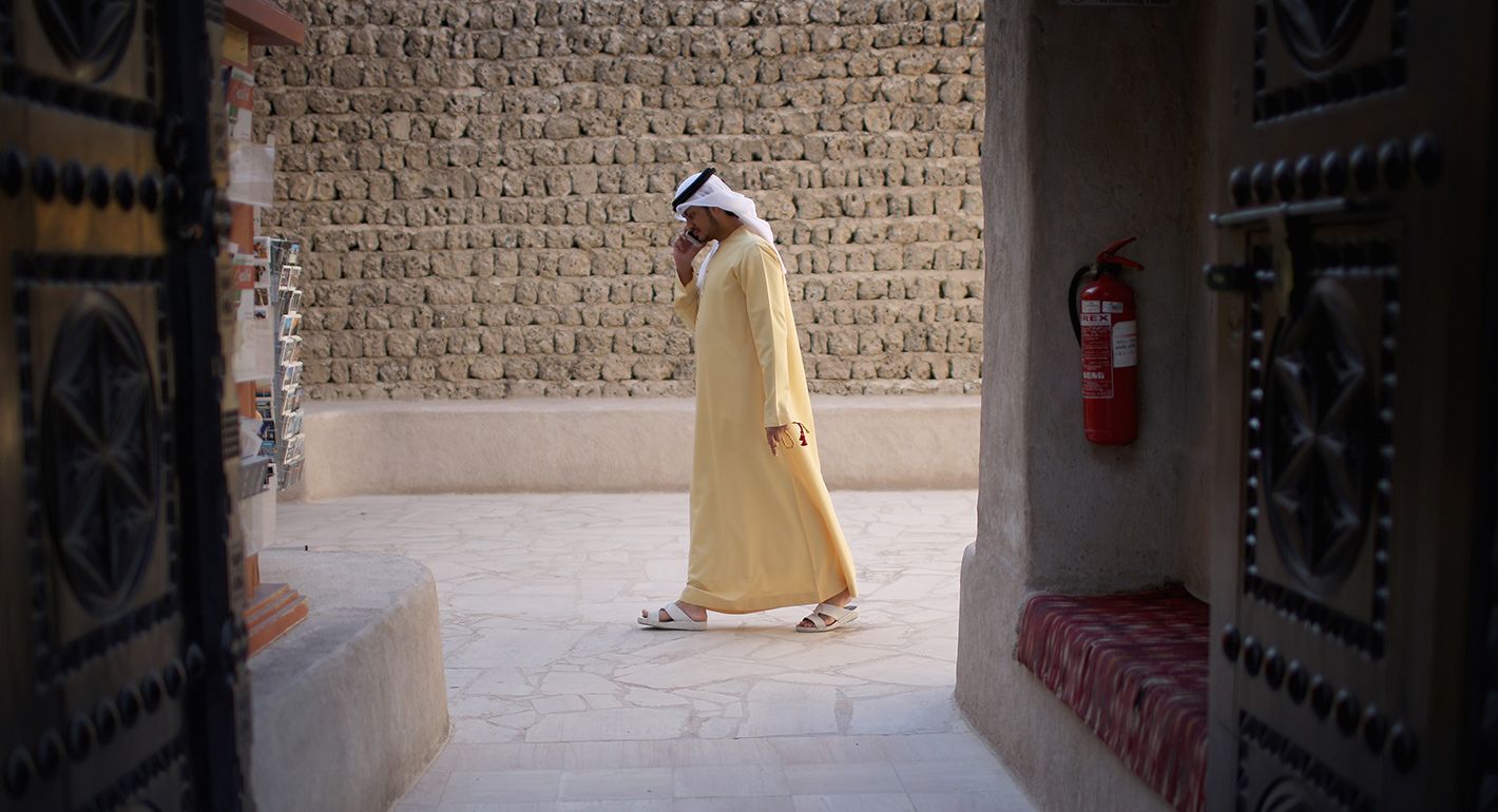 An Emerati man talks on his mobile phone as he walks through the Dubai Heritage Village in Dubai, United Arab Emirates.