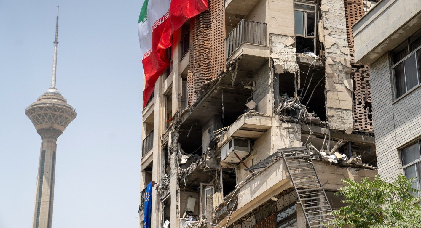 Building damaged and draped with an Iranian flag