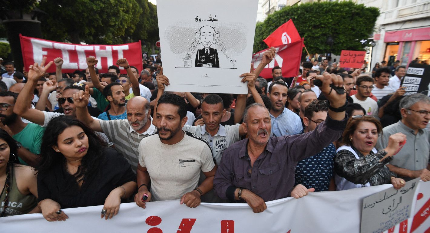 People marching and yelling while holding signs and banners