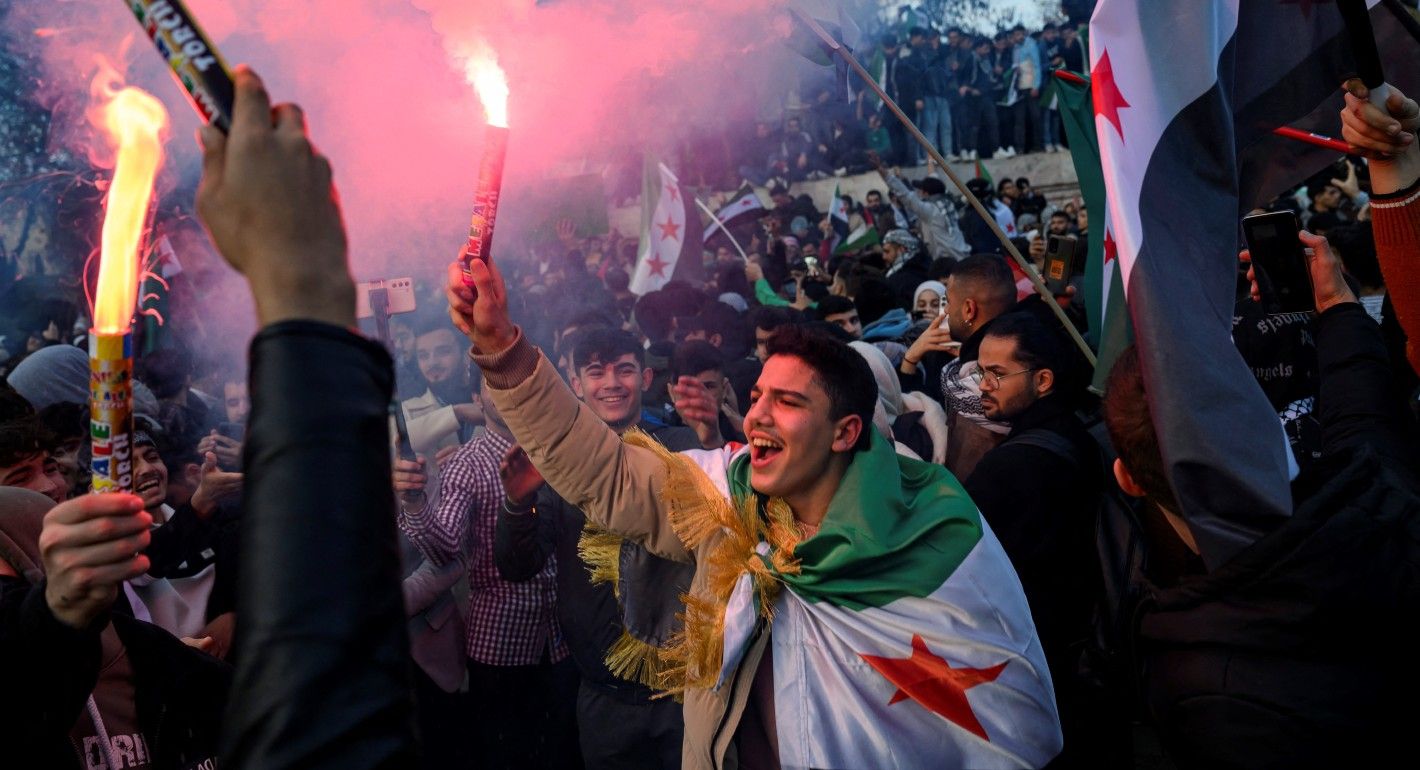 Crowd of people holding flares and flags