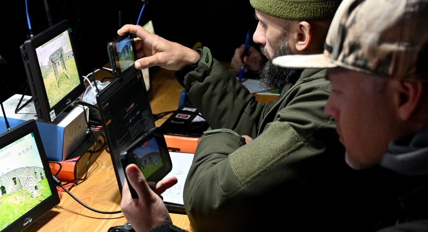 Photo of Ukrainian soldiers looking at several screens showing battlefields and drones.