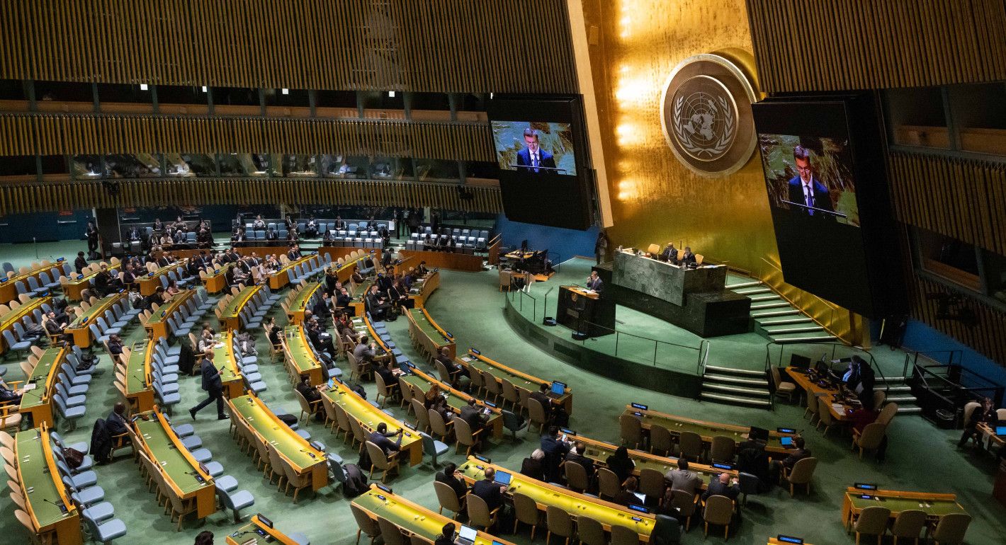 wide shot of a large, ornate meeting room with someone speaking