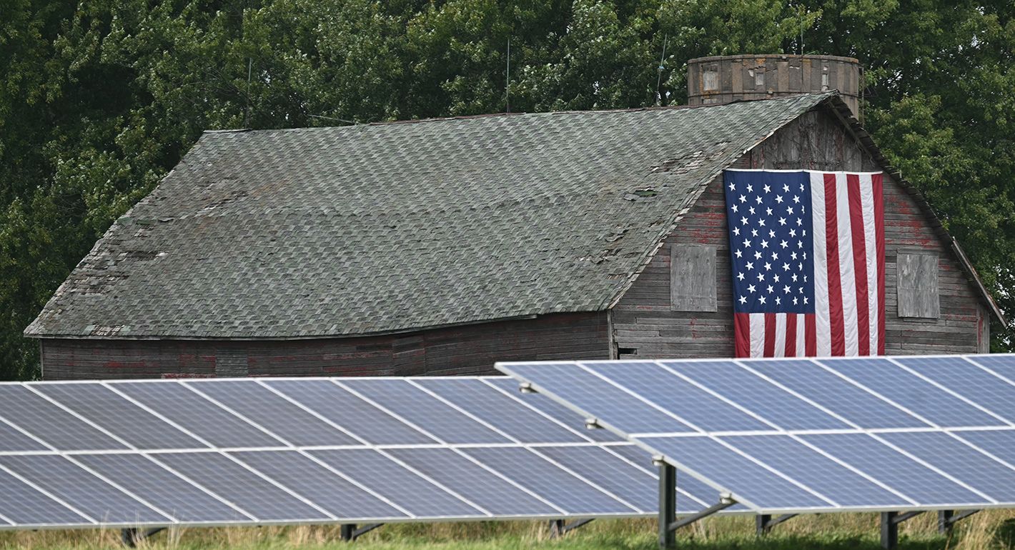 Solar panels in front of a barn with a U.S. flag