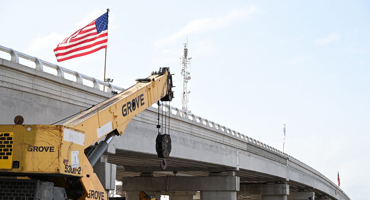 People walk near a construction site of a bridge as part of an interchange in the Koumassi district of Abidjan on May 6, 2025.