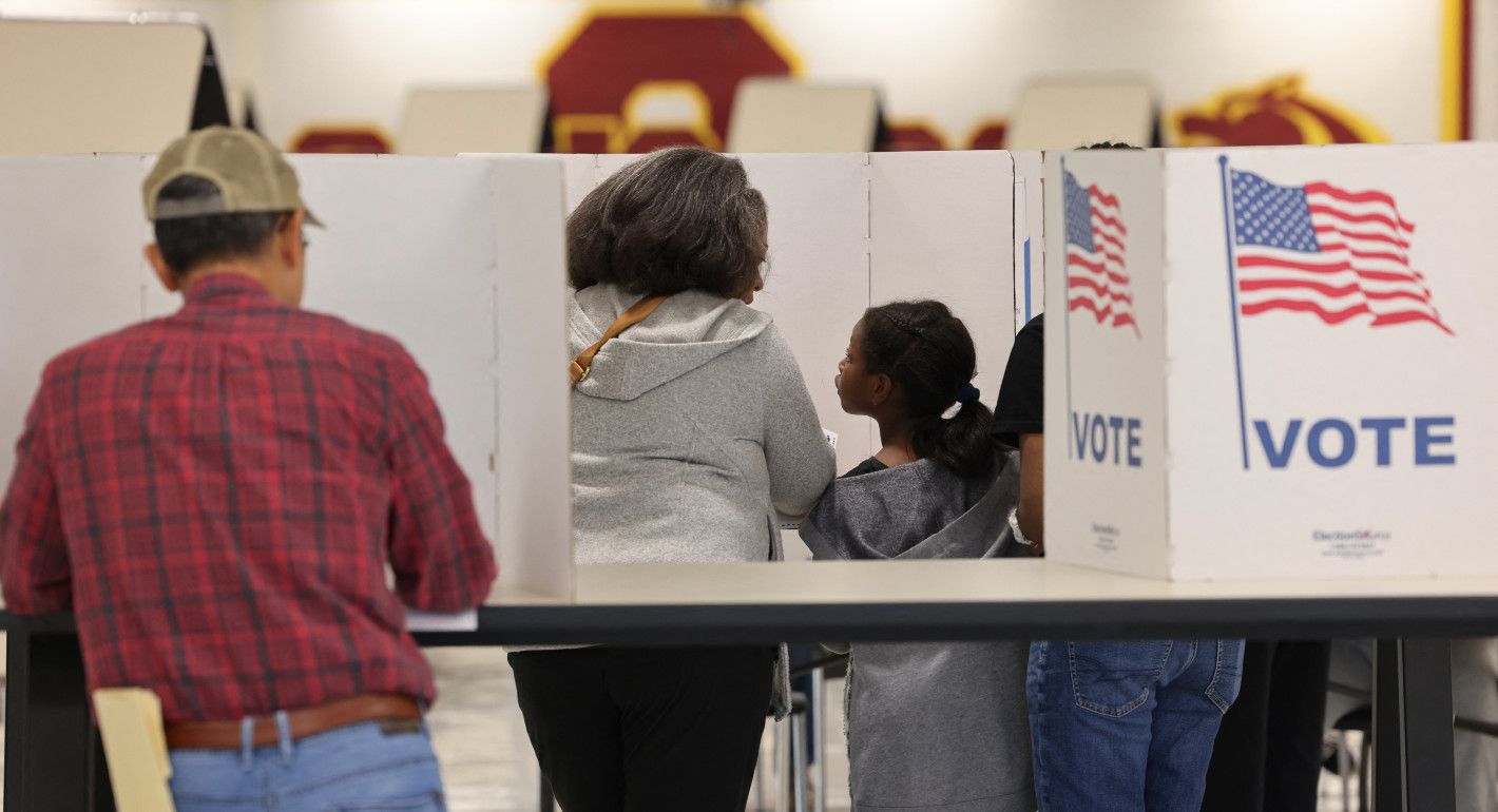 woman voting, with her young daughter watching